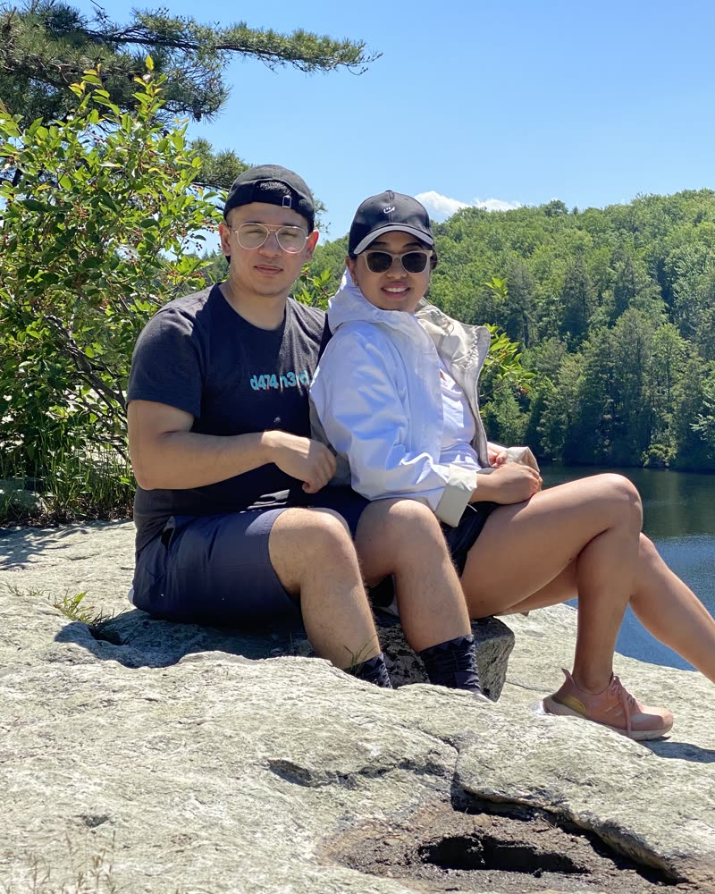 Jenesh and his wife on a sunny hike by a lake